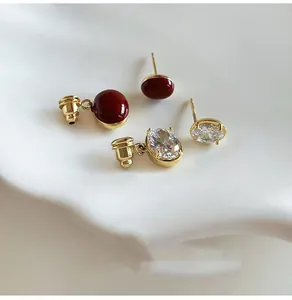 Primo piano di orecchini placcati oro con cabochon rosso e dettagli in zircone ovale.
