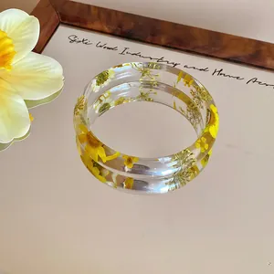 Macro view showing the intricate yellow dried flower details inside a clear acrylic bangle