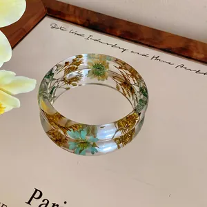 Detailed view of clear resin bangle embedded with natural colorful dried flowers