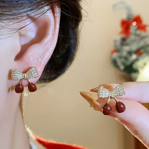 Vue détaillée de boucles d'oreilles nœud en zircon et cerise en émail rouge