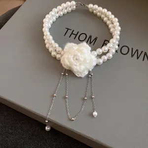 Detail view of a double-layer pearl choker with a delicate white knitted flower