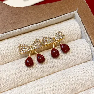 Détail macro de boucles d'oreilles nœud cerise dorées élégantes avec incrustations de zircons