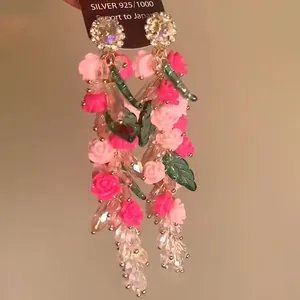 Vista detallada de pendientes de borla de cristal floral con rosas de resina rosa