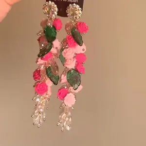 Vista detallada de pendientes de borla con flores de cristal y elegantes rosas rosas y hojas