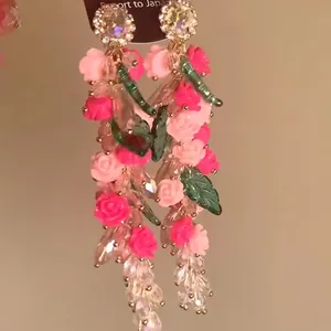Detalle de pendientes de borla de cristal con flores de rosa y brillantes de diamantes