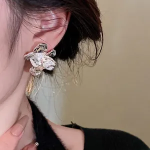Statement silver textured flower stud earrings with a stylish metallic finish on model
