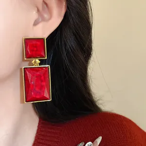Close-up view of vintage style red square geometric drop earrings worn on model's ear