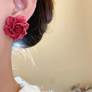 Close-up detail of an elegant red resin rose flower stud earring worn by a model