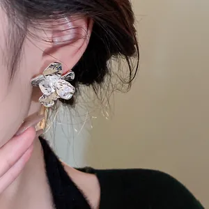 Close-up detail showing the texture of silver pleated flower stud earrings on model