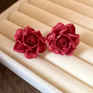 Detailed close-up of elegant vintage red resin rose stud earrings nestled in a white velvet jewelry box