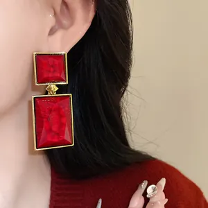 Close-up of vintage geometric red square earrings worn by a model for a stylish look.