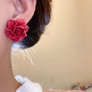 Close-up detailed shot of a vintage red resin rose flower stud earring on a model's ear