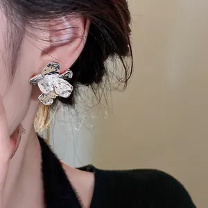 Detailed macro view of textured silver flower stud earring on model's ear showing style.