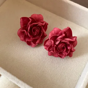 Detailed macro shot of vintage red resin rose earrings in a soft cream jewelry box