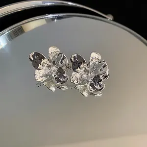 High-detail macro view of silver crumpled flower earrings with mirror reflection