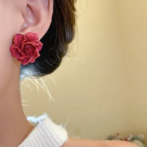 Close-up detail of a vintage deep pink resin rose stud earring worn on an earlobe elegantly