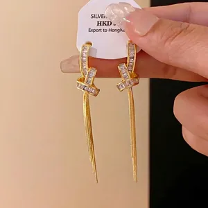 Eleganti orecchini a perno con nodo dorato, nappe e pietre di zirconia cubica brillanti
