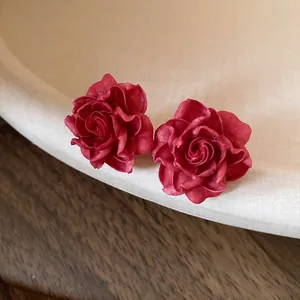 Close-up of red resin rose stud earrings with silver needles for a vintage look