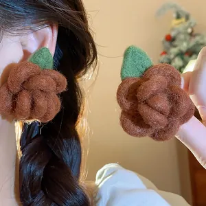Detailed view of handmade brown flocked rose stud earrings with a green leaf accent