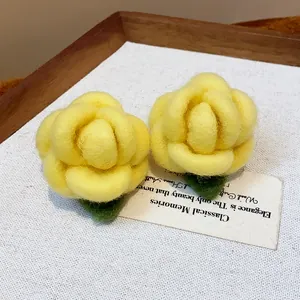 Detailed macro view of yellow flocked flower stud earrings on a textured background.