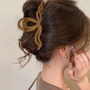Dettaglio di una molletta per capelli ondulata marrone opaco che modella uno chignon