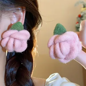 Detail view of pink felted flower earrings with soft flocked texture on model's ear