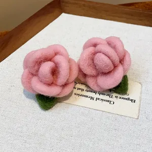 Detailed close-up of pink flocked rose earrings with green leaves on prop card.
