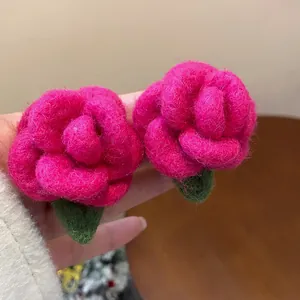 Detailed close-up view of fuchsia flocked rose stud earrings with green leaf details