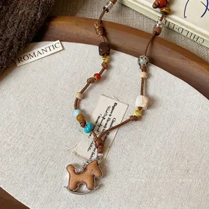 Handmade woven rocking horse necklace with leather pendant on a rustic flat lay background