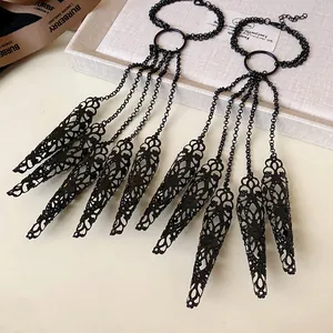 Close-up macro view of black hollow pattern finger nail caps with elegant tassel chain hand jewelry