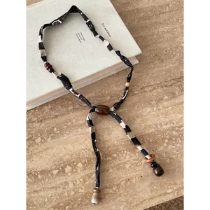 Dettaglio di una collana foulard etnica con perline su uno sfondo di libro minimale