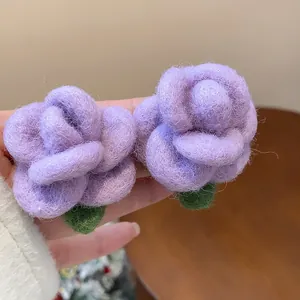 Macro view of soft purple flocked rose earrings with green leaf detail on silver needles