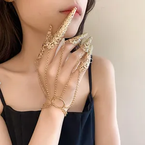 Detail of gold hollow pattern fingernail cover hand chain jewelry on female model