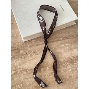 Vista dettagliata di una collana in tessuto marrone stile etnico con perline su libro.