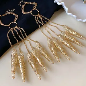 Detail showing the intricate hollow pattern and tassels of the gold nail cover bracelet.
