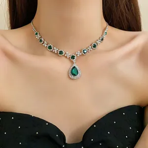 Dettaglio ravvicinato di una collana con ciondolo a goccia verde smeraldo su modella.