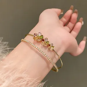 Detailed view of elegant double-layer gold bracelets with zirconia flowers on a wrist