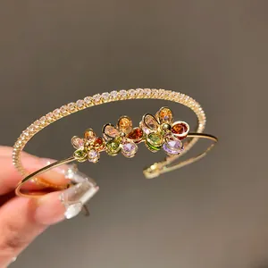 Close-up of an elegant double-layer gold cuff bracelet with colorful zircon flowers.