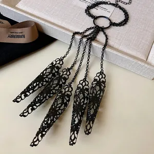 Close-up of black hollow-out floral pattern fingernail covers with elegant chain tassels