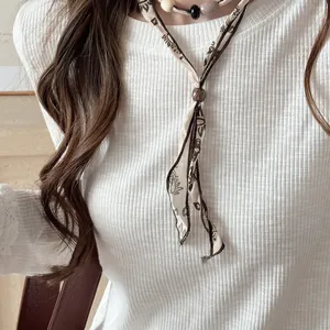 Dettaglio di una collana a sciarpa vintage in stile etnico con tessuto e perline