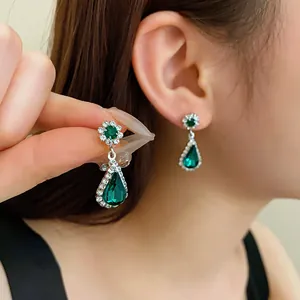 Primo piano di eleganti orecchini a goccia verde smeraldo con alone di cristallo