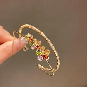 Detailed view of a golden double-layer open bangle with vibrant colorful zircon flowers