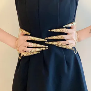 Detailed view of golden hollow filigree nail claw rings with tassel chain bracelet
