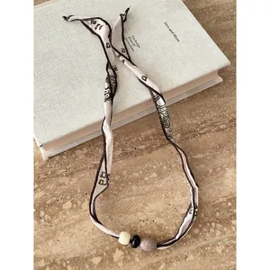 Dettaglio di una collana a sciarpa in tessuto con perline stile etnico vintage.