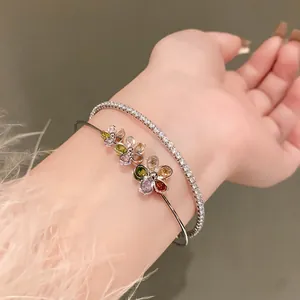 Close-up detail of silver open bangle with colorful zircon flowers and tennis bracelet.