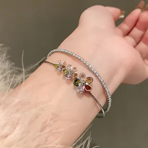 Detailed close-up of double-layer zircon flower bangle and tennis bracelet on a wrist.
