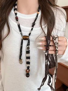 Dettaglio ravvicinato di collana sciarpa in tessuto stile etnico con perline