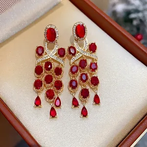 Boucles d'oreilles pendantes en zircon rouge style cour vintage dorées dans un écrin.