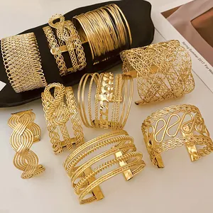 Collection of elegant golden minimalist layered open arm cuffs and wide metal bracelets