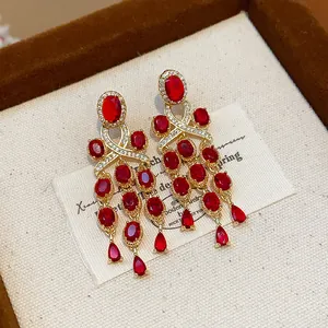 Gros plan sur des boucles d'oreilles dorées de style palais vintage avec glands en zircon rouge